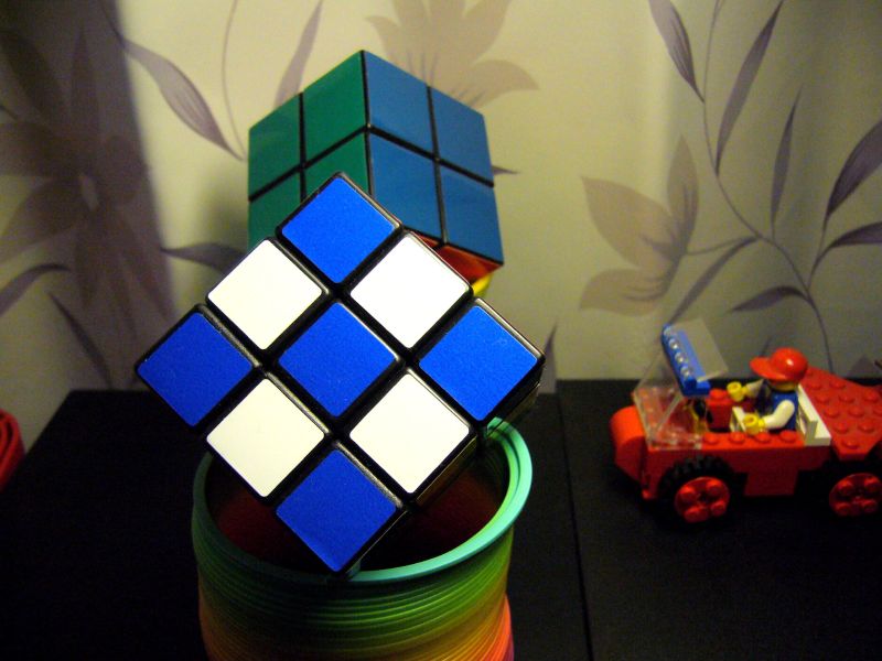 Zwei Rubik's Cubes auf einer Regenbogenfeder und ein Auto aus Lego