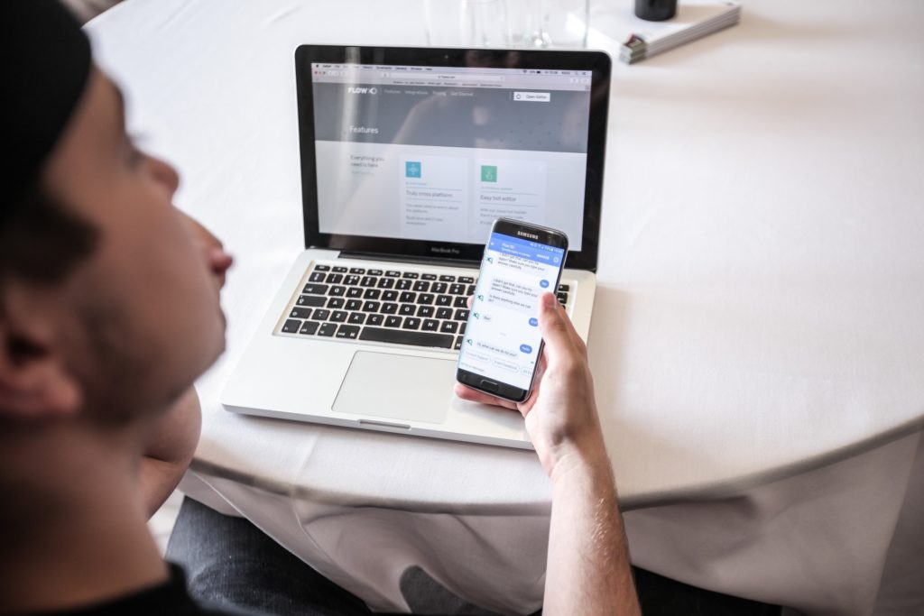 A man sitting at a table using a chatbot on a phone